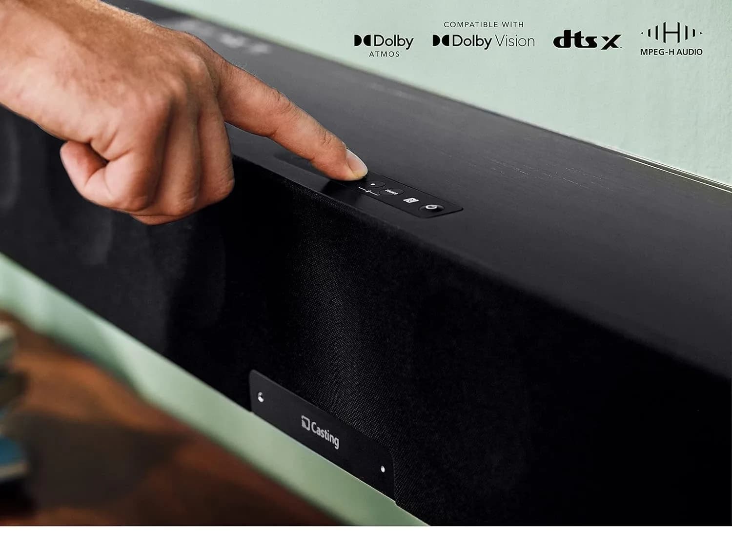 A hand pressing the touch controls on top of the AMBEO Soundbar Max