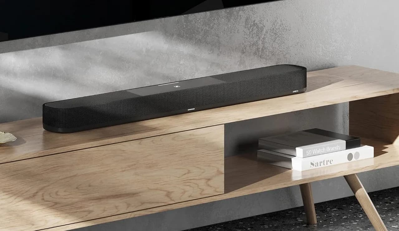 Sennheiser AMBEO Soundbar Plus on a wooden console beneath a television