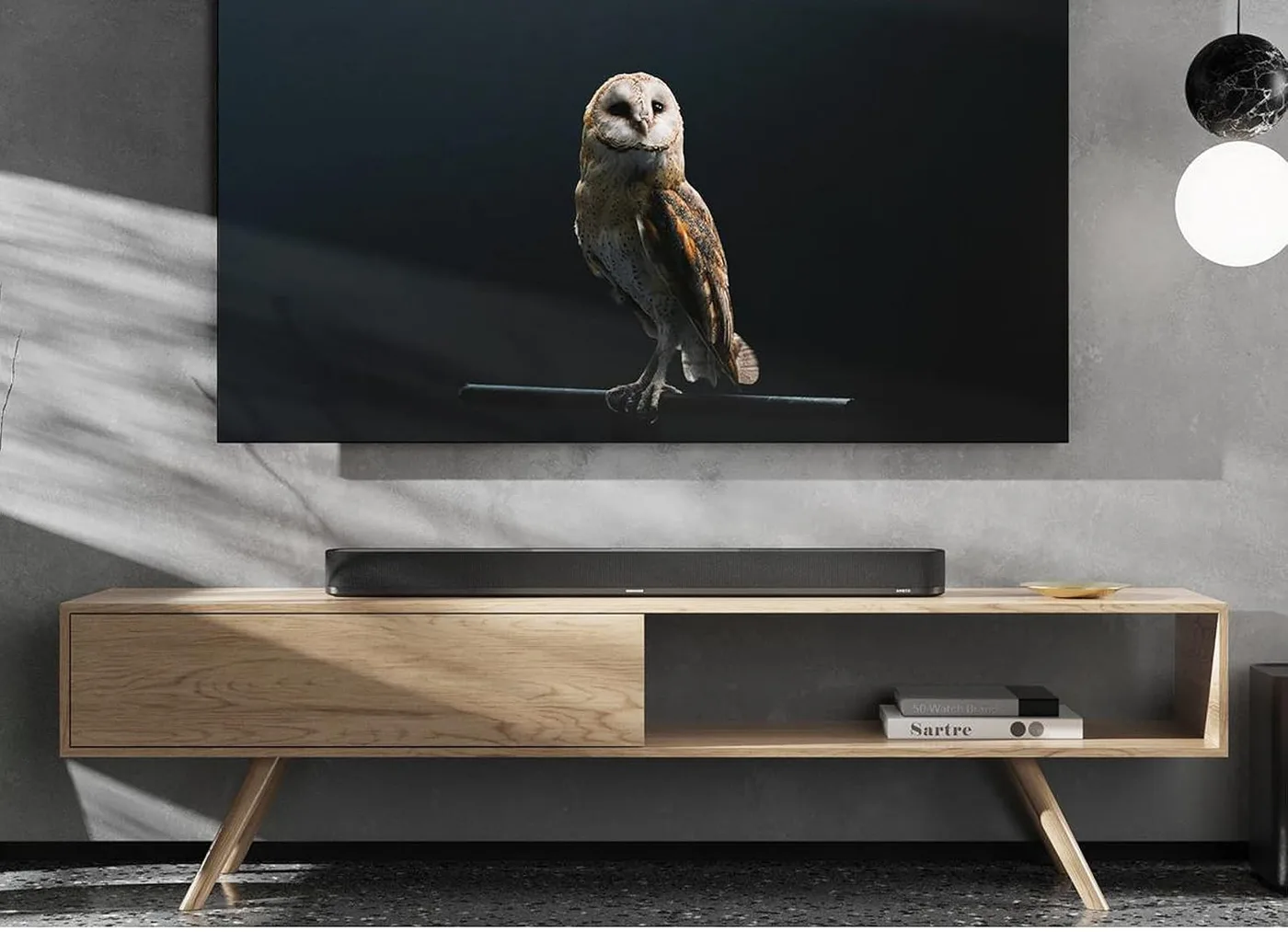 The AMBEO Soundbar Plus on a wooden console below a wall-mounted television